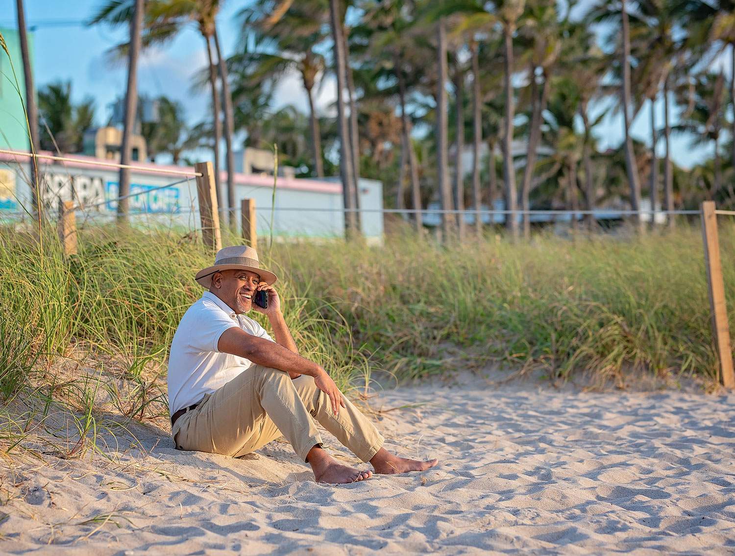 man sitting on sand while on the phone