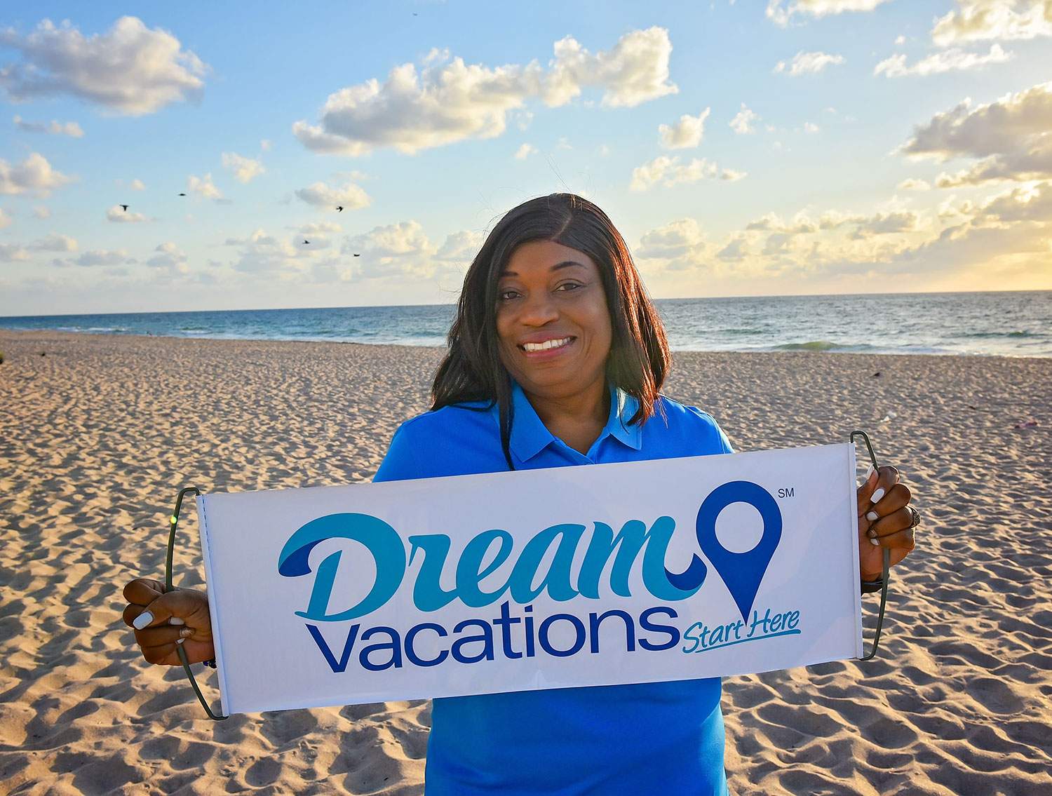 woman on the sand holding a Dream Vacations sign